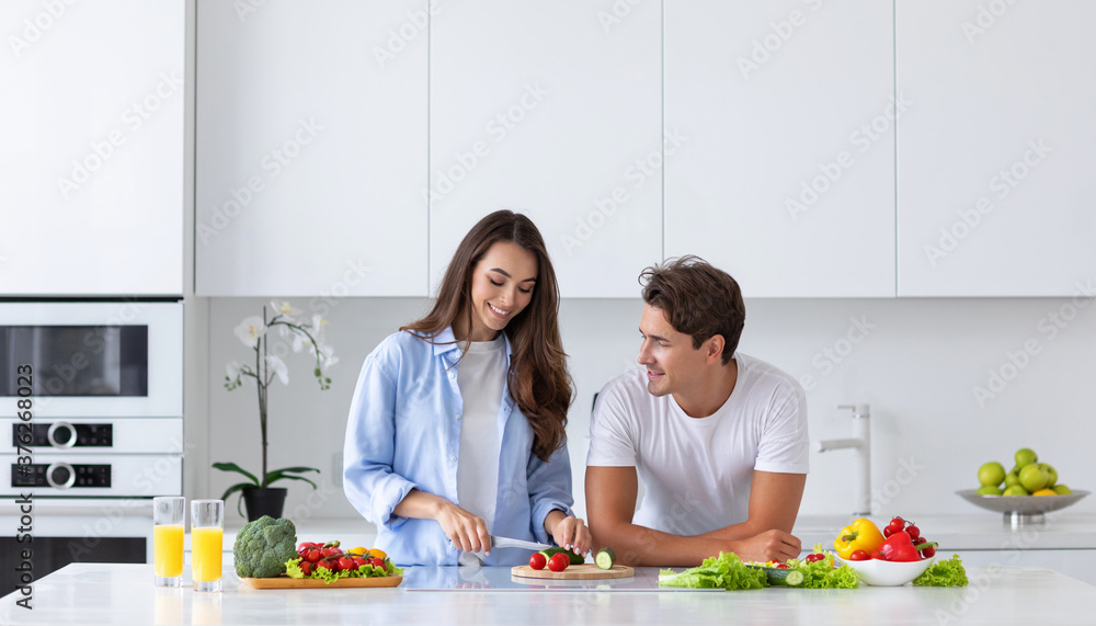 Loving couple preparing salad in kitchen at home.