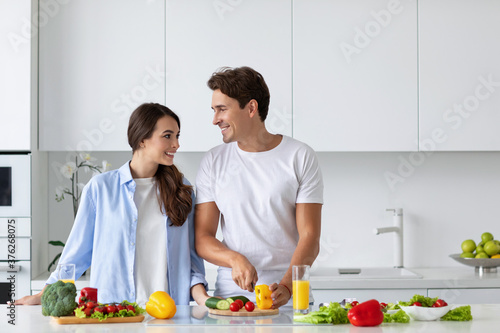 Cute couple cooking in kitchen, man chopping vegetables.