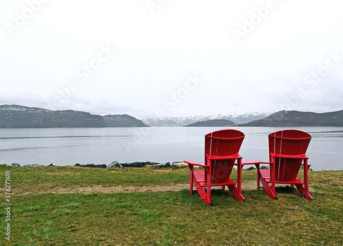 Red chairs in front of a lake in Gros Morne