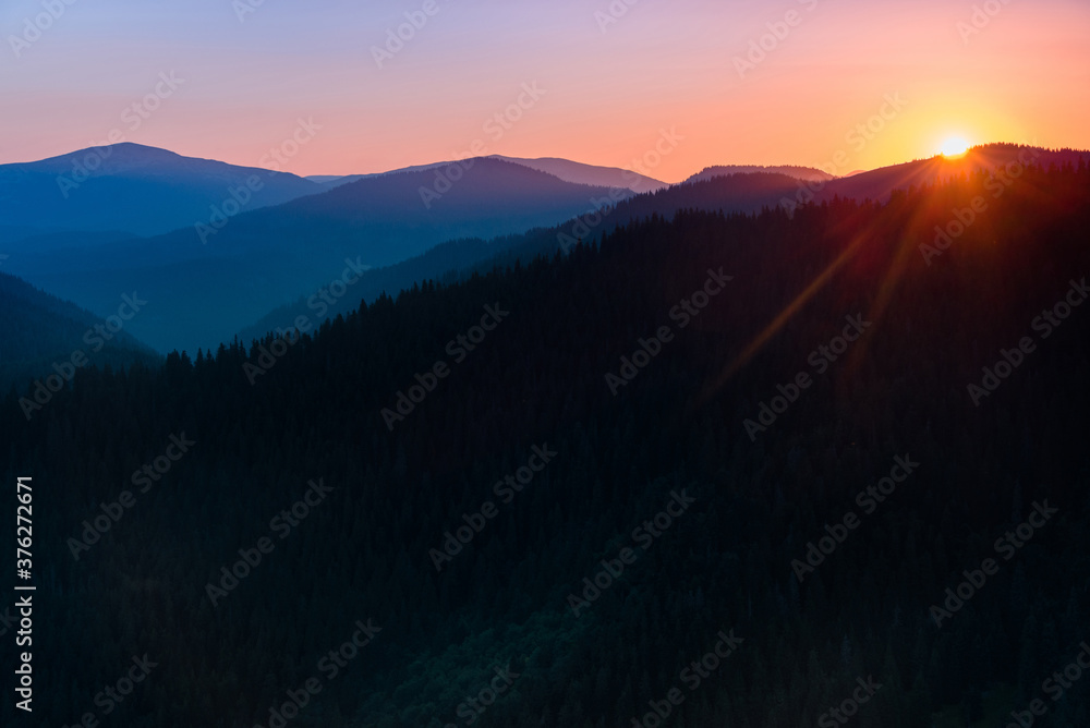 Great view of colorful sunrise in the mountains backlight glow against the sunlight with sun flare and bokeh. Concept of the awakening wildlife, emotional experience in your soul.