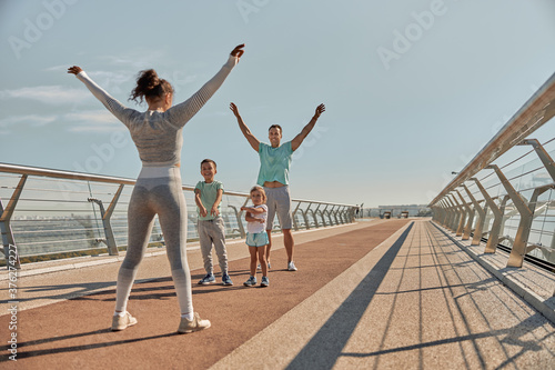 happy healthy and sporty family are doing workout trainings in sunny day