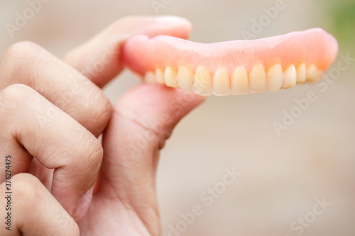 A man is holding dentures in his hands. Removable dentures flexible. False teeth.