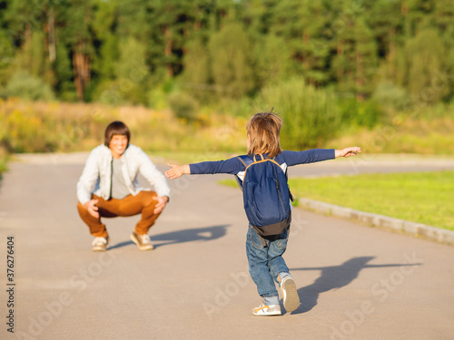 Father  picks up his son from kindergarten. Back to school after summer holidays. Family time, moral support. photo