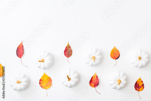 Flat lay pattern with colorful autumn leaves and pumpkins on a white background