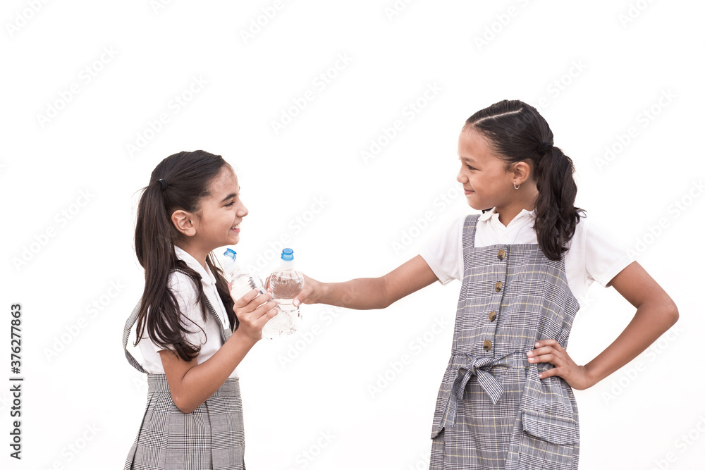 Two school girls wearing uniform toasting with water bottle on isolated white background. Two school girls wearing uniform toasting with water bottle on isolated white background.