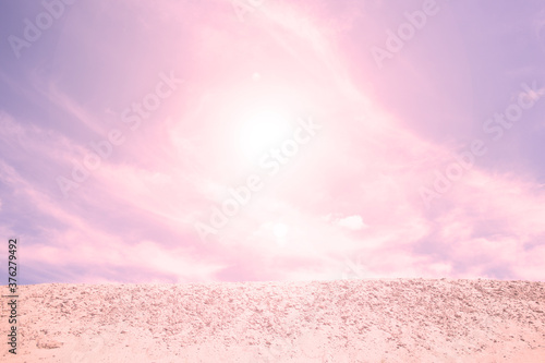 A bright sun shines in the sky above the sand in the desert