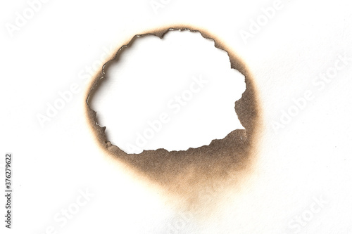 Fire burned hole white paper background texture. Paper burn mark stain