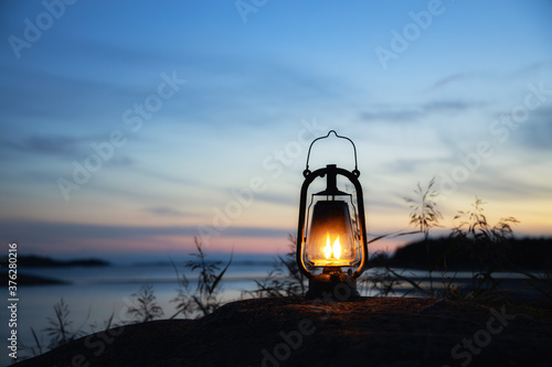 Fototapeta Naklejka Na Ścianę i Meble -  Beautiful old rustic oil lamp silhouette in a beautiful amazing sunset sky at island in baltic sea. Popular tourist destination in Finland.
