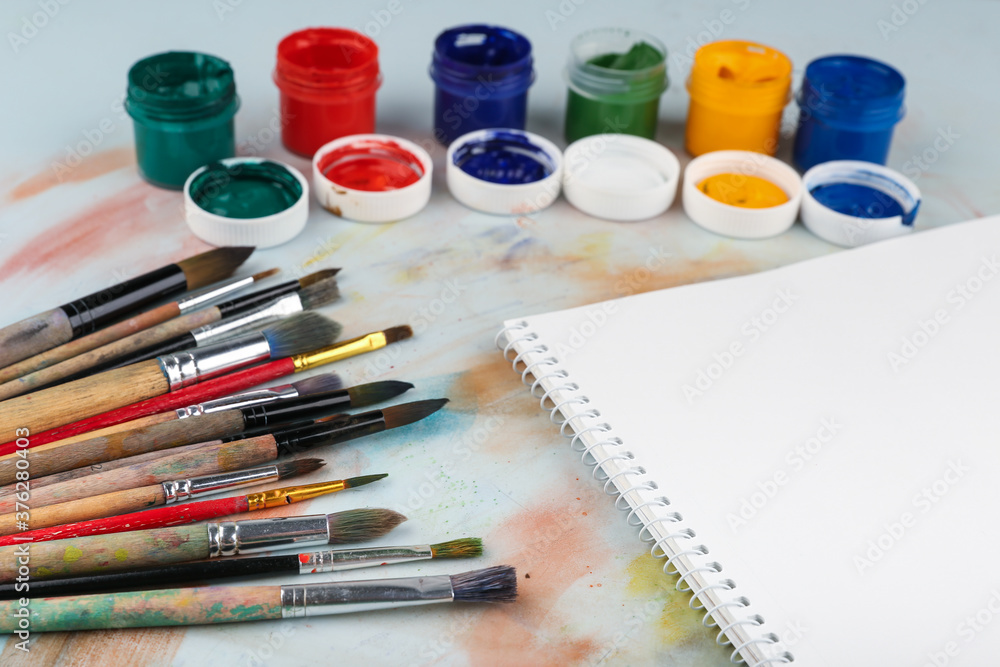 sketchbook, paint brushes and paints top view with copy space sketchbook, paint brushes and paints top view with copy space