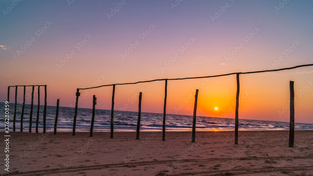 wooden poles on the beach at sunset glow