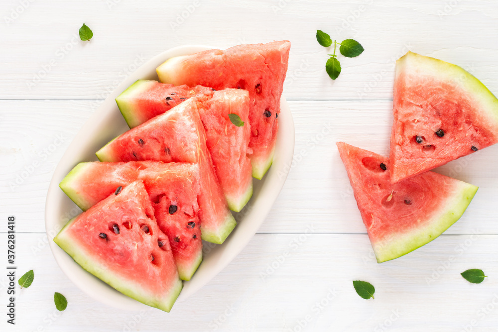 Juicy ripe sweet red watermelon slices with mint in a plate on a white background, top view Juicy ripe sweet red watermelon slices with mint in a plate on a white background, top view