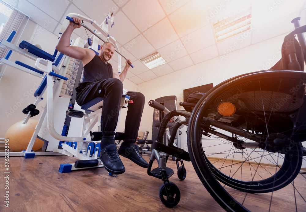 Obraz premium Disabled man doing strength exercises separate from the wheelchair.