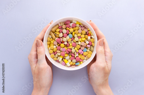 Creative medicine health concept photo of woman hands holding plate with medical pills on grey background.