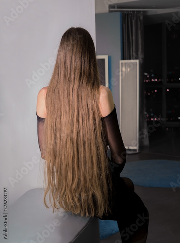 Back view of model with long natural hair sitting in room photo