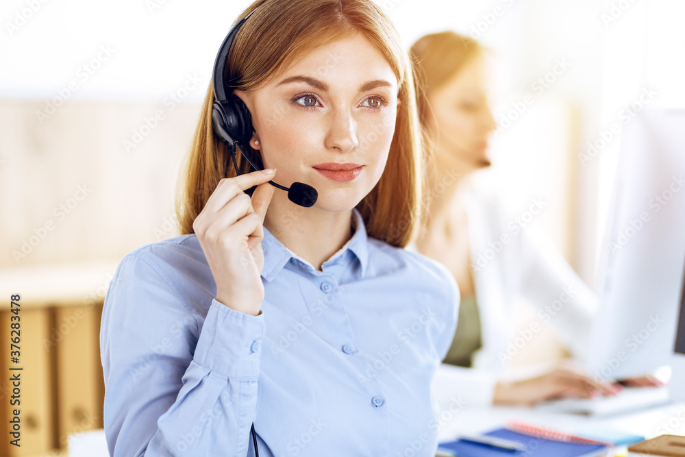 Portrait of call center operator at work in sunny office. Group of people in a headset ready to help customers. Business concept Portrait of call center operator at work in sunny office. Group of people in a headset ready to help customers. Business concept