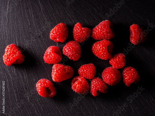 Macro photograph of several raspberries on a black background.