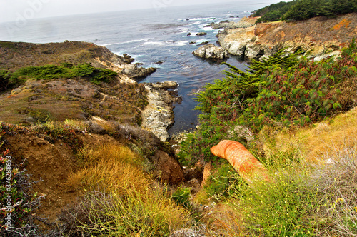 Headward Erosion has undermined culvert.  A section of sheared off corrugated pipe is being buried downslope by eroding hillside, Highway 1 south of Carmel, California  photo