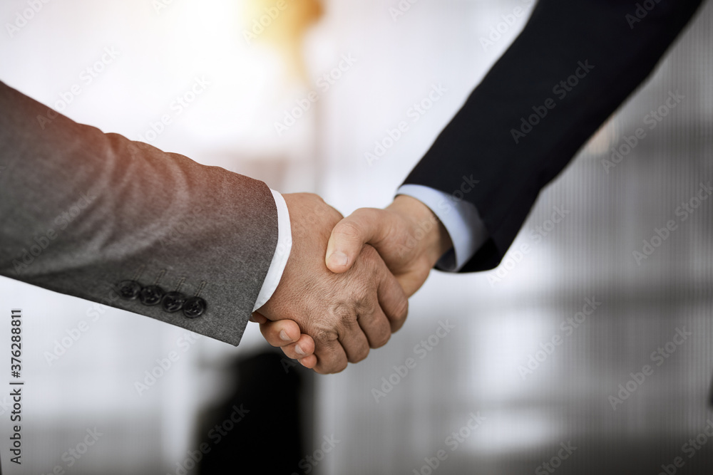 Business people standing and shaking hands in sunny office, close-up. Handshake and marketing Business people standing and shaking hands in sunny office, close-up. Handshake and marketing