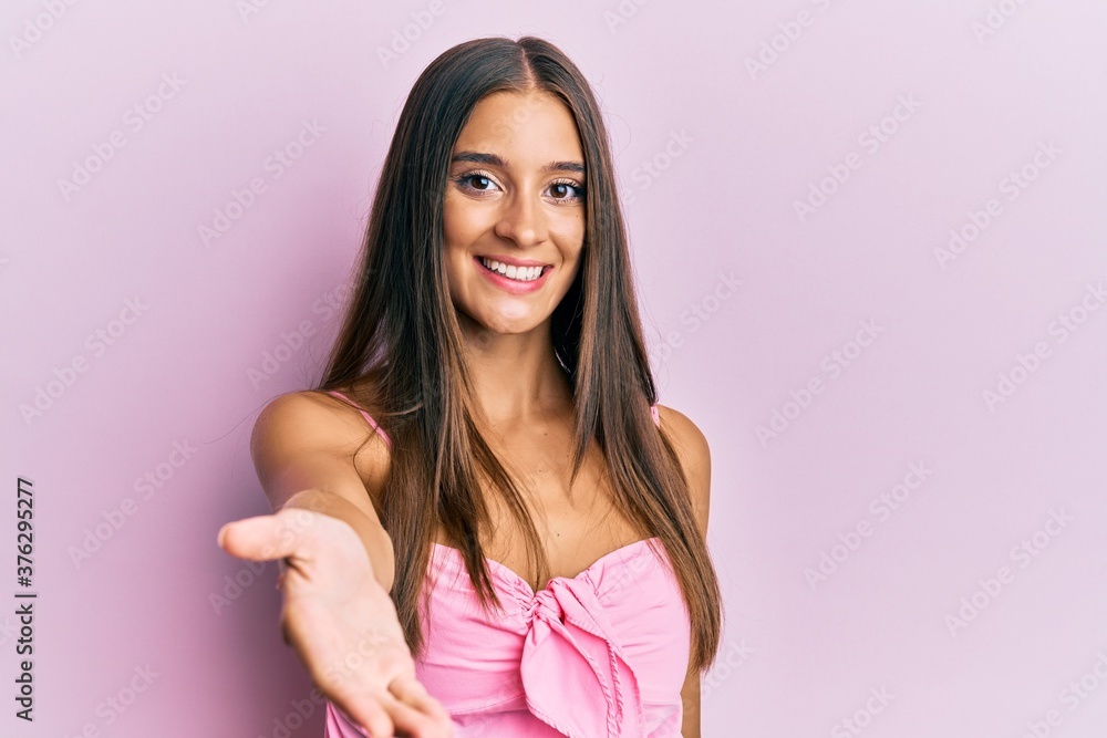 Young hispanic woman wearing casual style with sleeveless shirt smiling cheerful offering palm hand giving assistance and acceptance. Young hispanic woman wearing casual style with sleeveless shirt smiling cheerful offering palm hand giving assistance and acceptance.