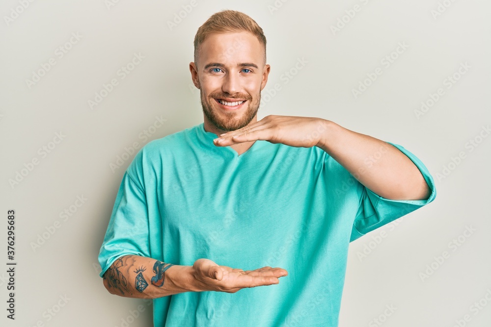 Young caucasian man wearing casual clothes gesturing with hands showing big and large size sign, measure symbol. smiling looking at the camera. measuring concept. Young caucasian man wearing casual clothes gesturing with hands showing big and large size sign, measure symbol. smiling looking at the camera. measuring concept.