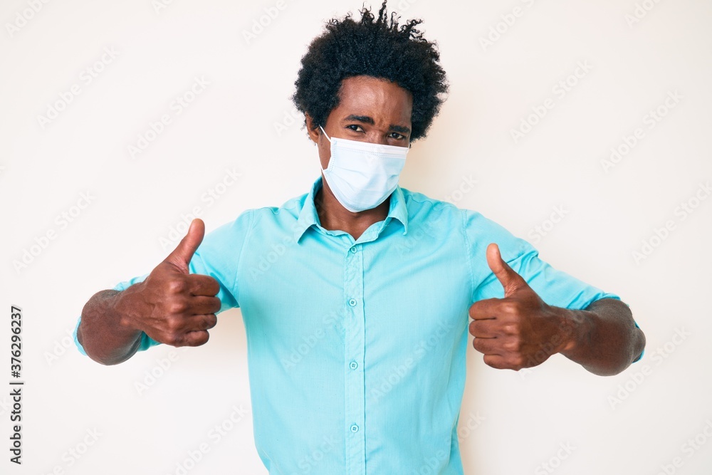 Handsome african american man with afro hair wearing medical mask skeptic and nervous, frowning upset because of problem. negative person. Handsome african american man with afro hair wearing medical mask skeptic and nervous, frowning upset because of problem. negative person.