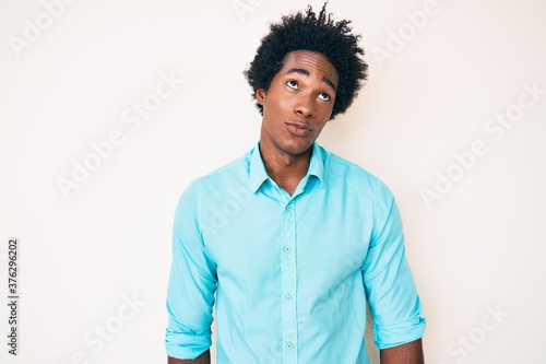 Handsome african american man with afro hair wearing casual clothes smiling looking to the side and staring away thinking.