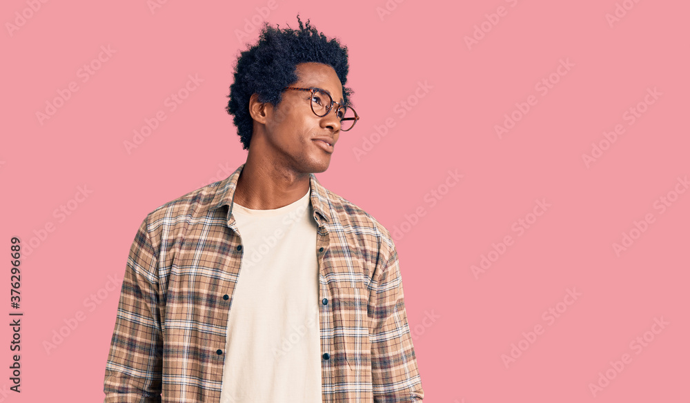 Handsome african american man with afro hair wearing casual clothes and glasses smiling looking to the side and staring away thinking. Handsome african american man with afro hair wearing casual clothes and glasses smiling looking to the side and staring away thinking.
