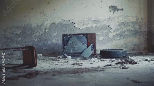 Throwing a rock to an abandoned television, broken screen in old television. Slow motion