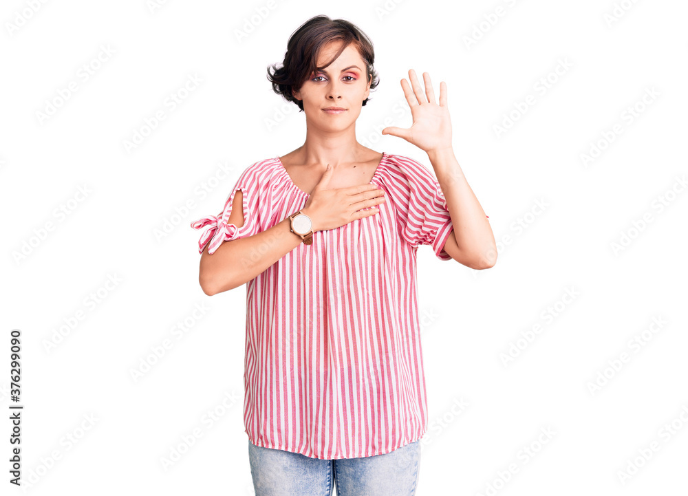 Beautiful young woman with short hair wearing casual summer clothes swearing with hand on chest and open palm, making a loyalty promise oath Beautiful young woman with short hair wearing casual summer clothes swearing with hand on chest and open palm, making a loyalty promise oath