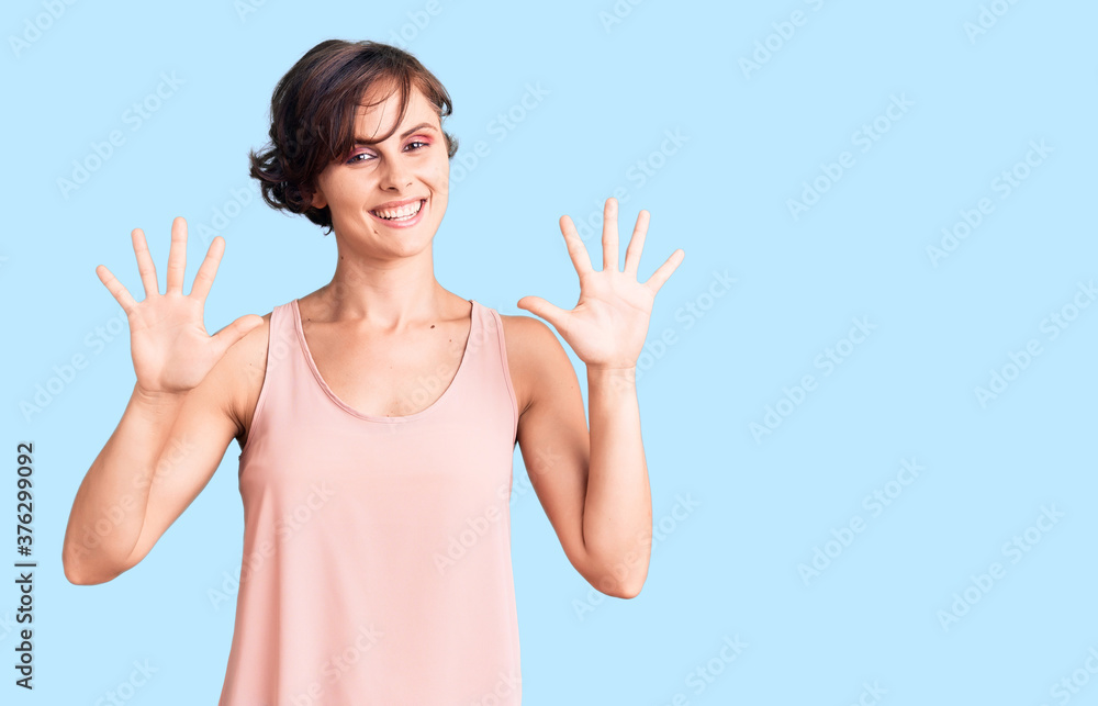 Beautiful young woman with short hair wearing casual style with sleeveless shirt showing and pointing up with fingers number ten while smiling confident and happy. Beautiful young woman with short hair wearing casual style with sleeveless shirt showing and pointing up with fingers number ten while smiling confident and happy.