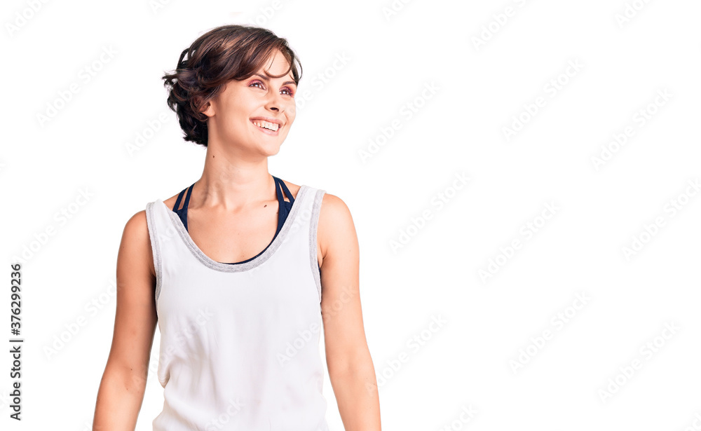 Beautiful young woman with short hair wearing casual sport clothes looking away to side with smile on face, natural expression. laughing confident. Beautiful young woman with short hair wearing casual sport clothes looking away to side with smile on face, natural expression. laughing confident.