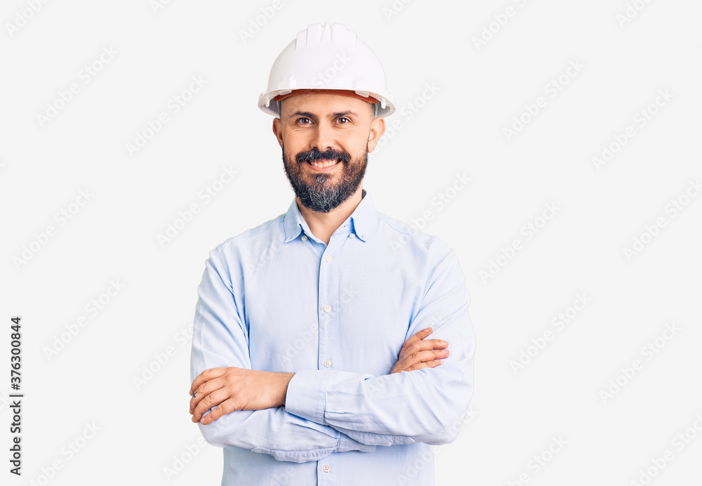 Young handsome man wearing architect hardhat happy face smiling with crossed arms looking at the camera. positive person. Young handsome man wearing architect hardhat happy face smiling with crossed arms looking at the camera. positive person.
