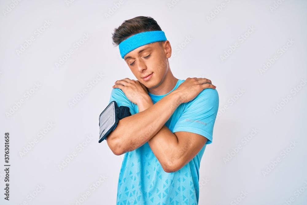 Young hispanic boy wearing sportswear hugging oneself happy and positive, smiling confident. self love and self care Young hispanic boy wearing sportswear hugging oneself happy and positive, smiling confident. self love and self care