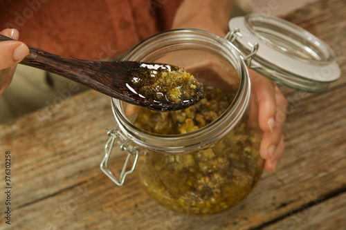 Herbal infused oil. Yellow immortelle flowers and cold pressed olive oil in a glass jar. Process of maceration.