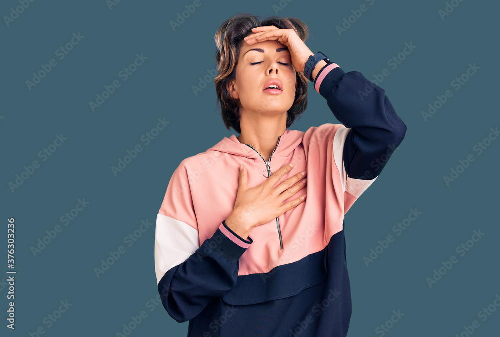 Young beautiful woman wearing sportswear touching forehead for illness and fever, flu and cold, virus sick Young beautiful woman wearing sportswear touching forehead for illness and fever, flu and cold, virus sick