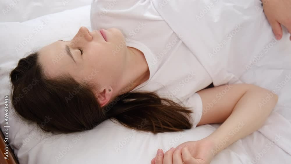Close up of cute beautiful woman slowly waking up in morning, gets up from comfortable white bed at home. Young attractive girl greets new day. Сoncept of sleep and rest on weekend Close up of cute beautiful woman slowly waking up in morning, gets up from comfortable white bed at home. Young attractive girl greets new day. Сoncept of sleep and rest on weekend