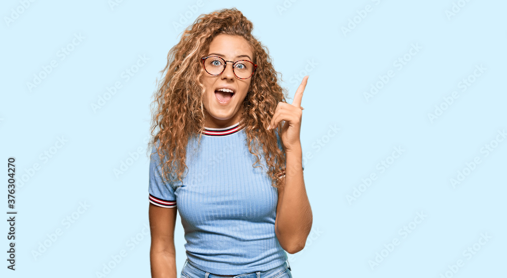Beautiful caucasian teenager girl wearing casual clothes and glasses pointing finger up with successful idea. exited and happy. number one. Beautiful caucasian teenager girl wearing casual clothes and glasses pointing finger up with successful idea. exited and happy. number one.