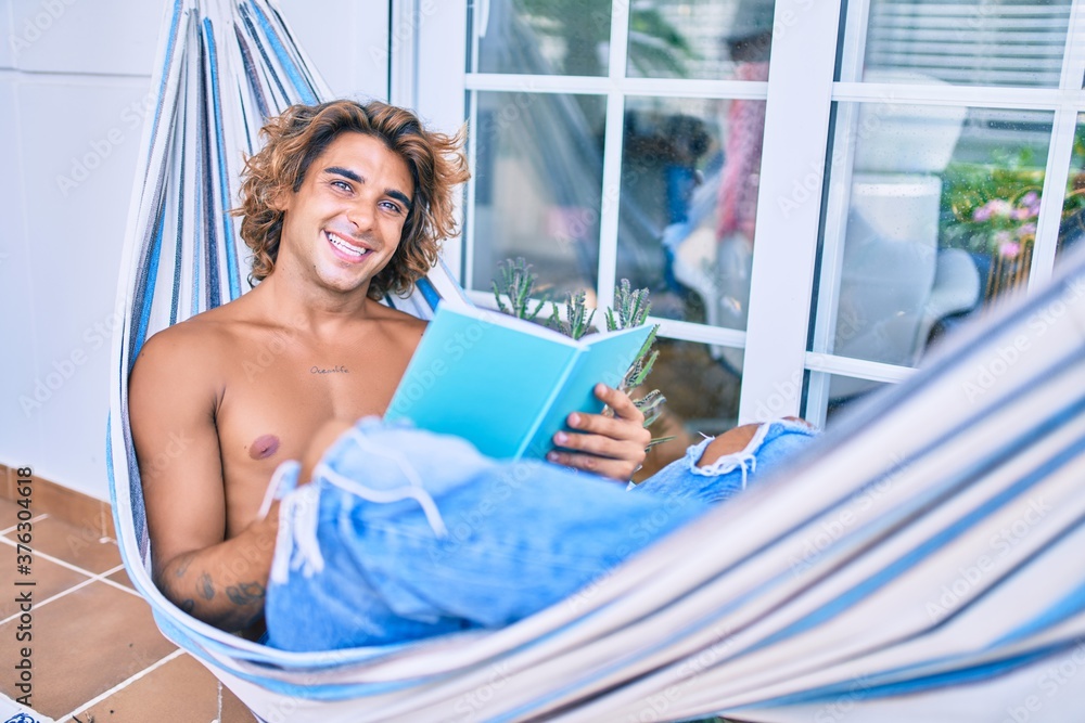 Young hispanic man relaxed reading book lying on the hammock at terrace. Young hispanic man relaxed reading book lying on the hammock at terrace.