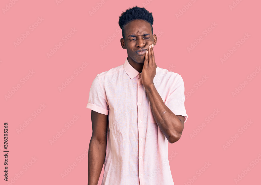 Young african american man wearing casual clothes touching mouth with hand with painful expression because of toothache or dental illness on teeth. dentist Young african american man wearing casual clothes touching mouth with hand with painful expression because of toothache or dental illness on teeth. dentist