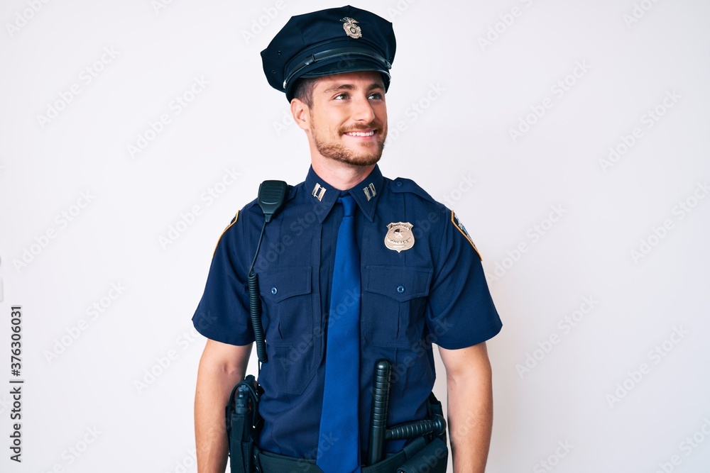 Young caucasian man wearing police uniform looking away to side with smile on face, natural expression. laughing confident. Young caucasian man wearing police uniform looking away to side with smile on face, natural expression. laughing confident.