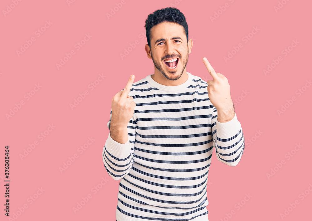 Naklejka premium Young hispanic man wearing casual clothes showing middle finger doing fuck you bad expression, provocation and rude attitude. screaming excited