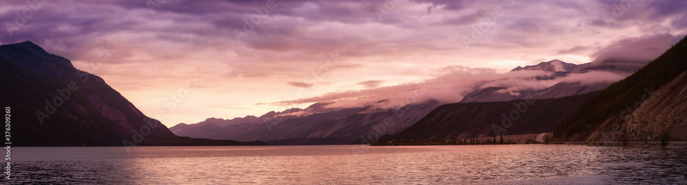Beautiful Panoramic View of Muncho Lake in the Canadian Northern Rockies during a cloudy sunrise. Taken in British Columbia, Canada. Nature Background Panorama