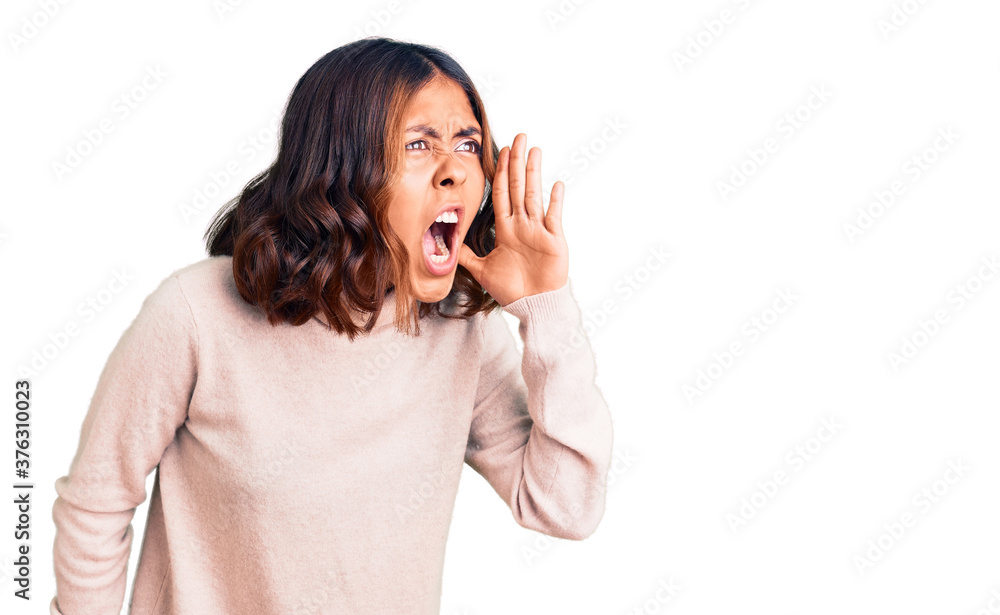 Young beautiful mixed race woman wearing winter turtleneck sweater shouting and screaming loud to side with hand on mouth. communication concept.