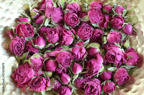 Dried rose flowers on a golden platter. View from above. Closeup