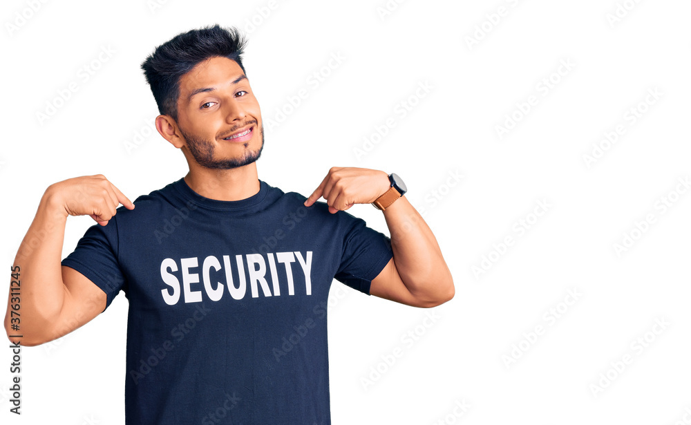 Handsome latin american young man wearing security t shirt looking confident with smile on face, pointing oneself with fingers proud and happy. Handsome latin american young man wearing security t shirt looking confident with smile on face, pointing oneself with fingers proud and happy.