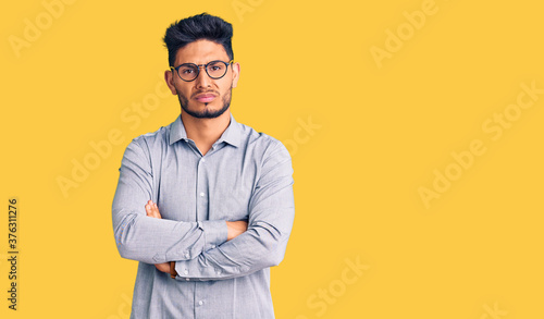 Handsome latin american young man wearing business clothes and glasses skeptic and nervous, disapproving expression on face with crossed arms. negative person.