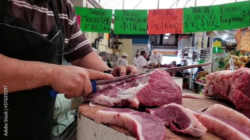 Carnicero con cubrebocas cortando la carne en el mercado  photo