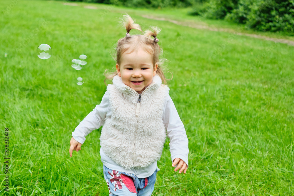 Caucasian kid happy running in a summer park with soap bubbles Caucasian kid happy running in a summer park with soap bubbles