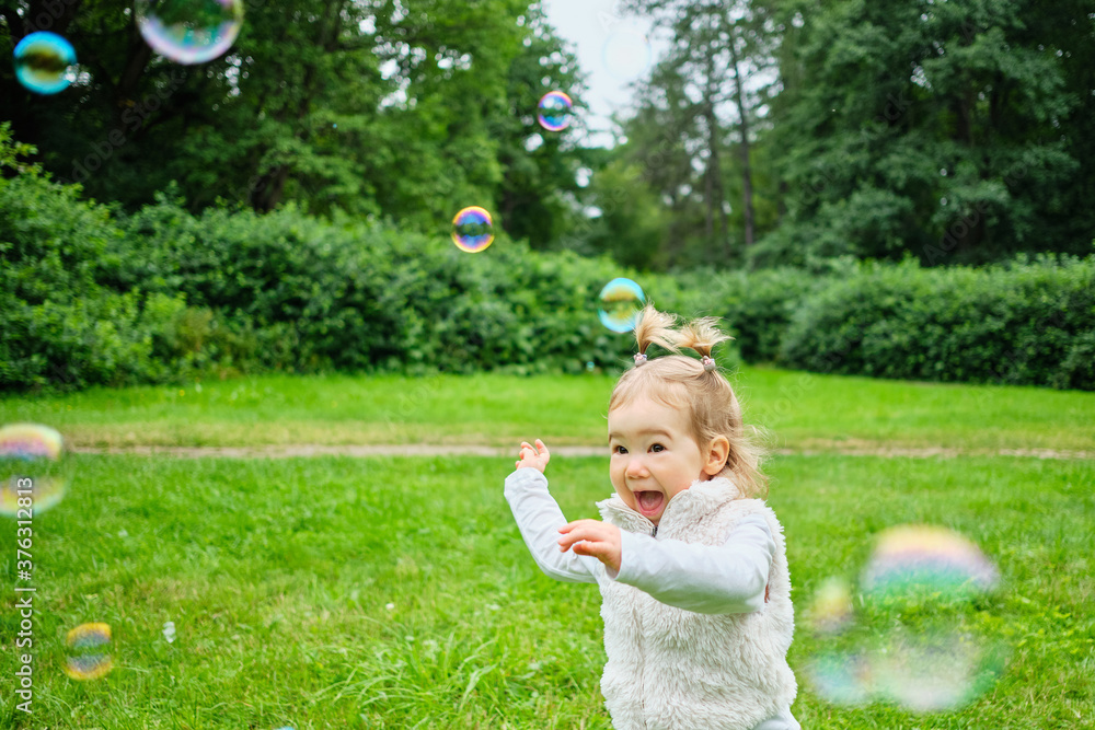 Caucasian kid happy running after soap bubbles in the park Caucasian kid happy running after soap bubbles in the park