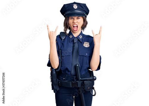 Young beautiful girl wearing police uniform shouting with crazy expression doing rock symbol with hands up. music star. heavy concept.